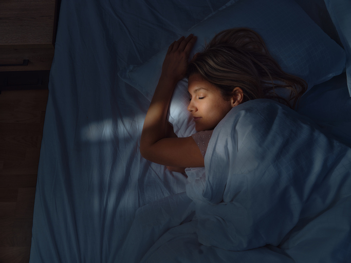 Above view of young woman sleeping in bed at night.